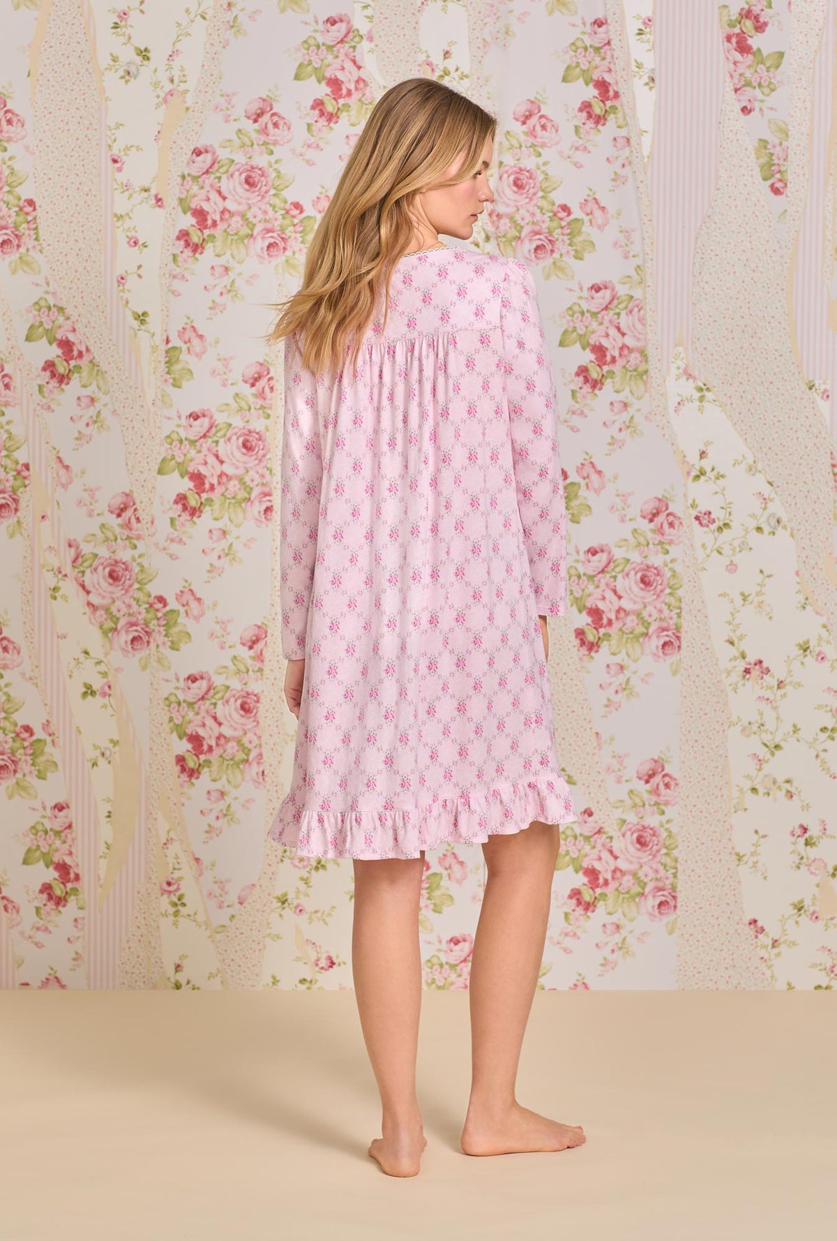 A lady wearing pink long sleeve short cotton knit nightgown with trellis rose print.